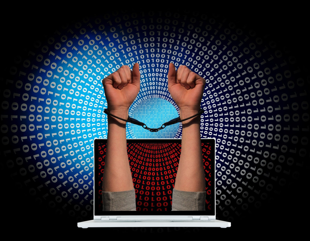 Manos con esposas saliendo de una pantalla